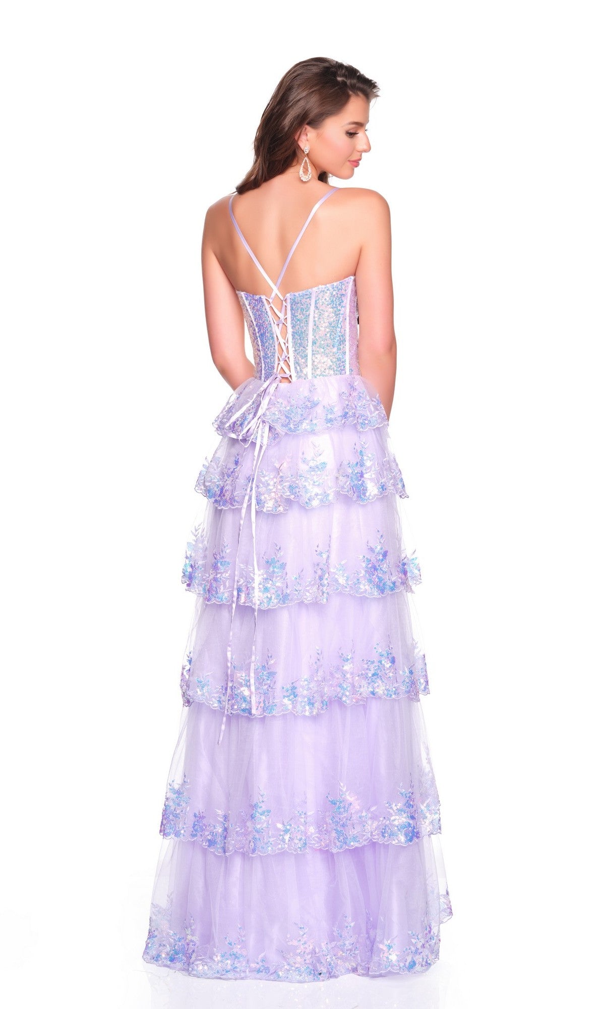 A woman faces away in the Dave and Johnny 12636, a light-purple long prom dress with floral details, lace-up back, spaghetti straps, and a tiered tulle skirt that creates an elegant silhouette.